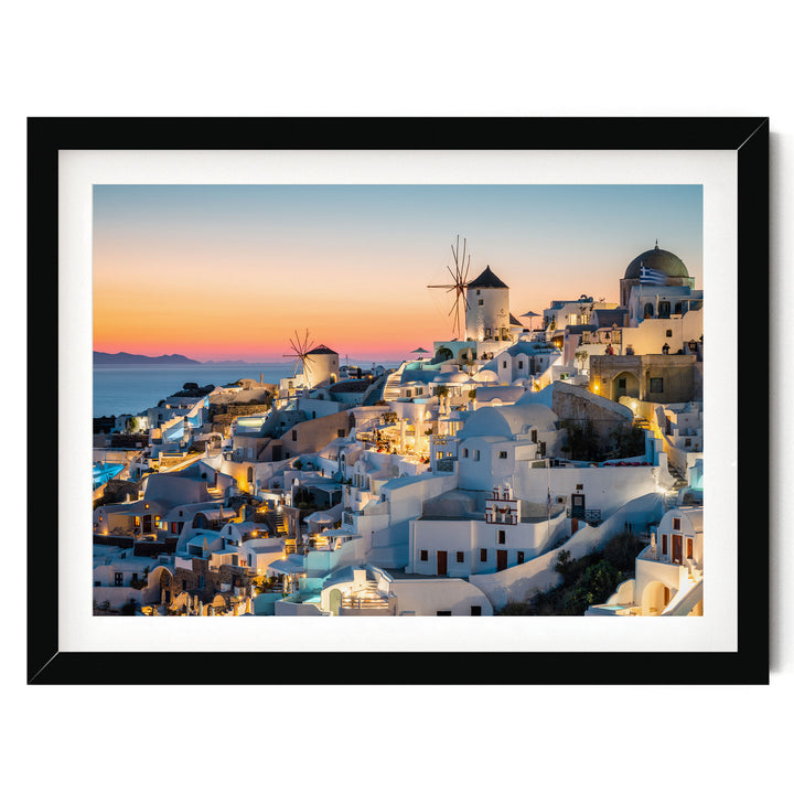 a picturesque coastal town with white buildings and windmills, set against a stunning sunset sky.