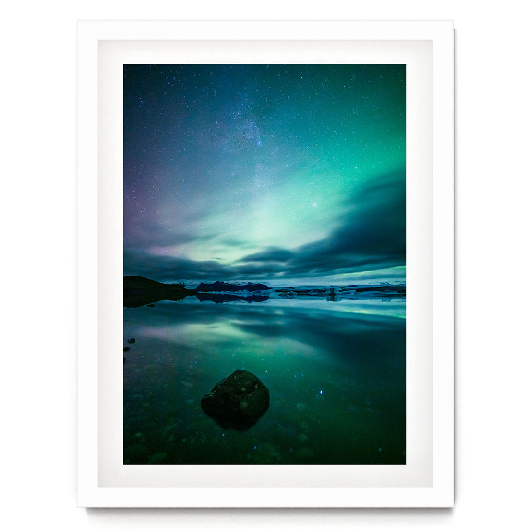 a serene night scene with a calm body of water reflecting the vibrant colors of the night sky, including the mesmerizing northern lights.