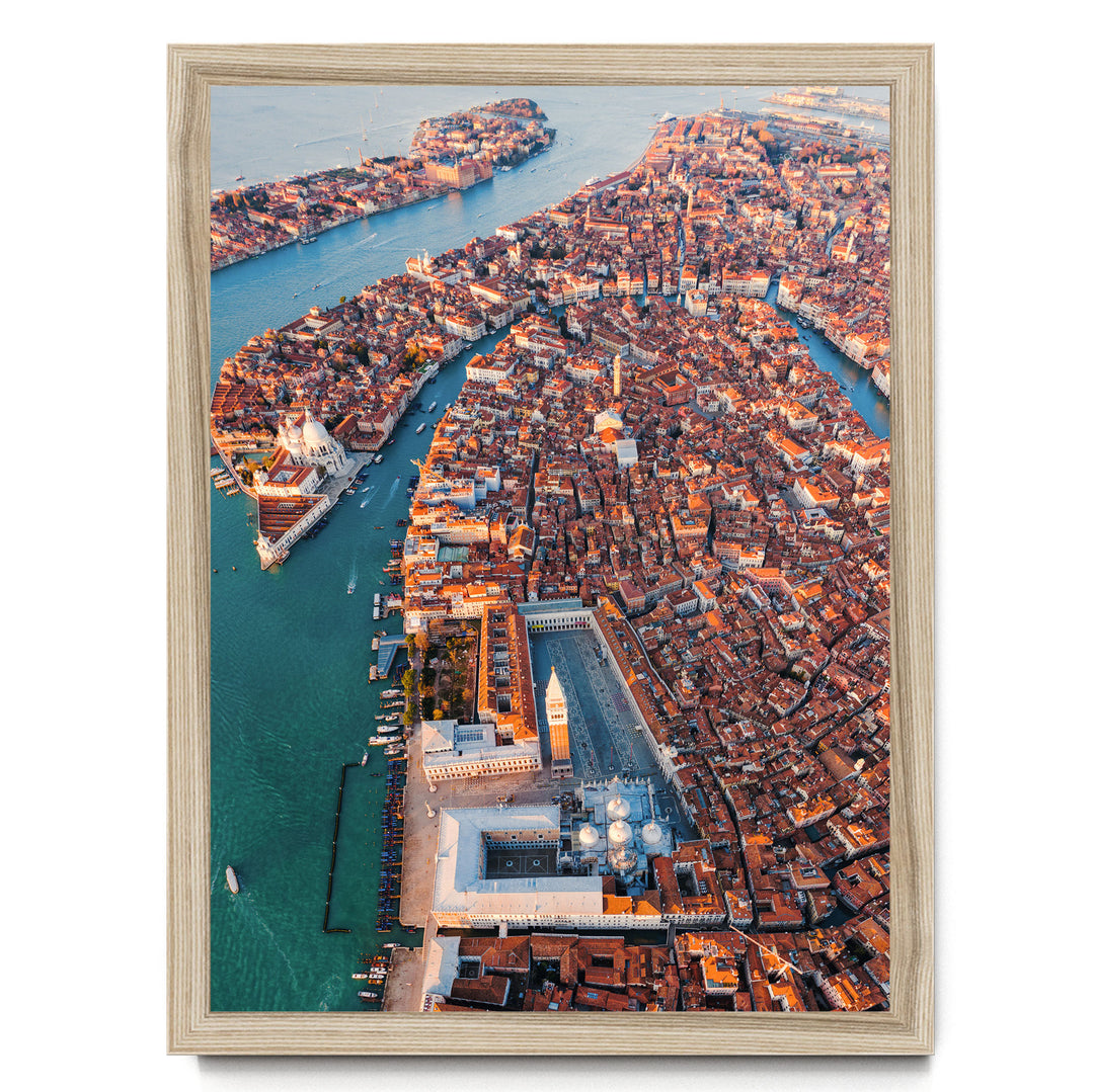 The image is an aerial view of a densely populated city with a river running through it. The city is characterized by a mix of old and new buildings, with a large white building featuring a clock tower in the center. The city is surrounded by water, and there are several boats visible on the river. The image is framed and appears to be a collage of multiple images, with no specific focus on any particular element.