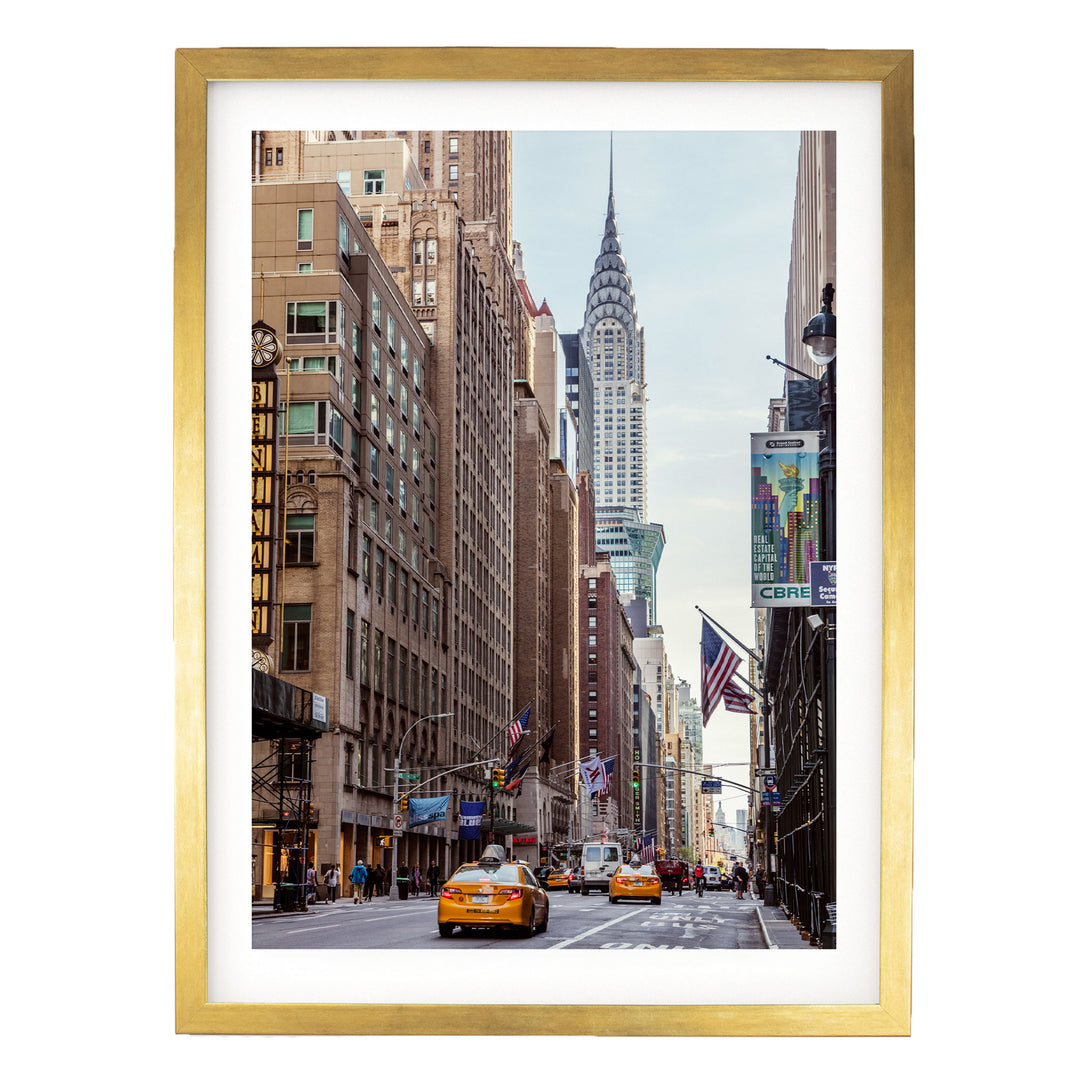 A bustling city street with tall buildings, including the iconic New York City skyline, and yellow taxis driving along the road.