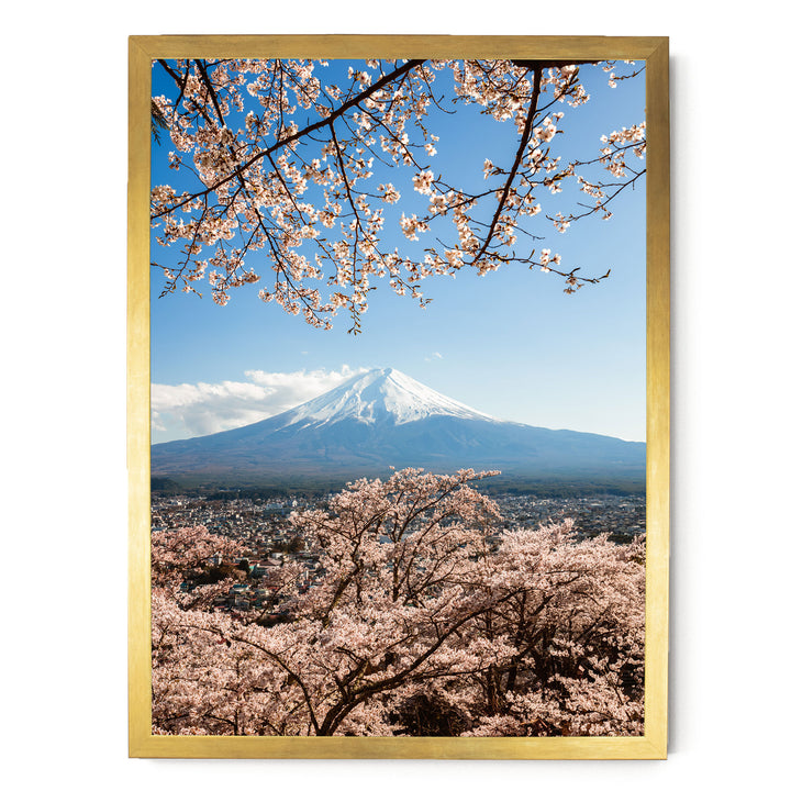 A breathtaking view of Mount Fuji, the iconic Japanese volcano, with its snow-capped peak rising majestically against a clear blue sky, framed by cherry blossom trees in full bloom.