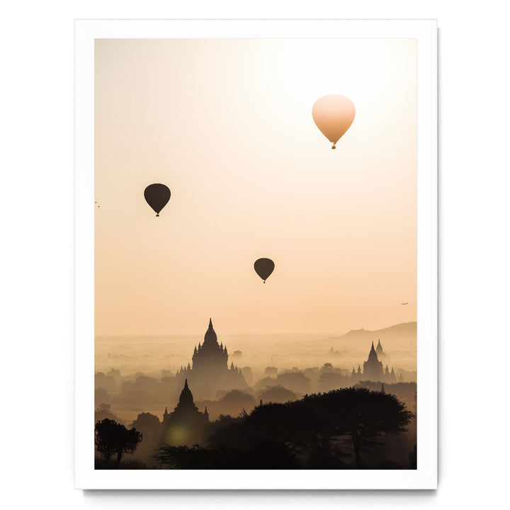 three hot air balloons floating in the sky above a cityscape with silhouetted buildings.