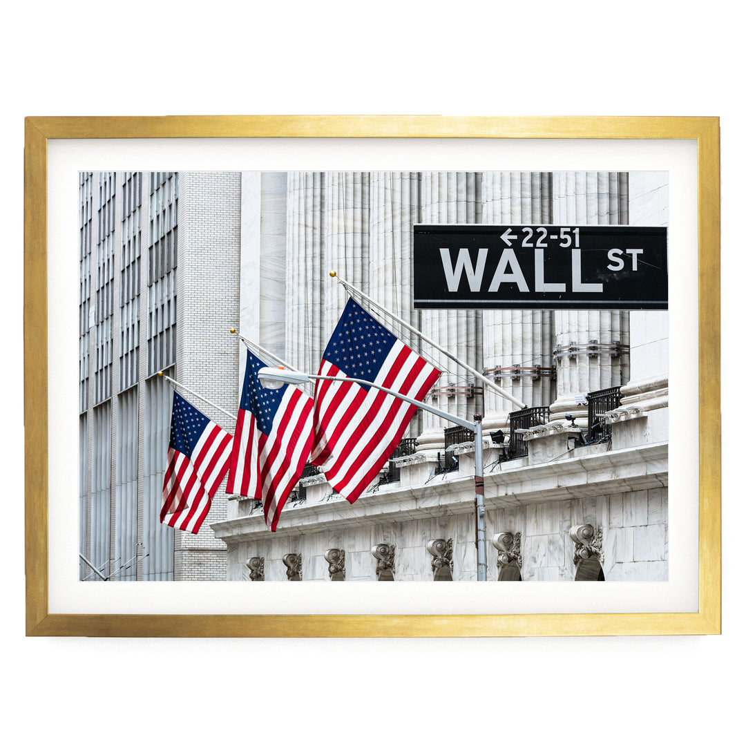 three American flags flying in front of a building with a Wall Street sign.