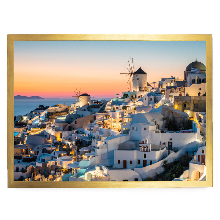 a picturesque coastal town with white buildings and windmills, set against a stunning sunset sky.
