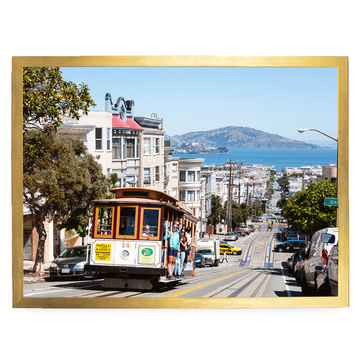A cable car is traveling down a busy street in San Francisco, with buildings, cars, and pedestrians visible in the background.