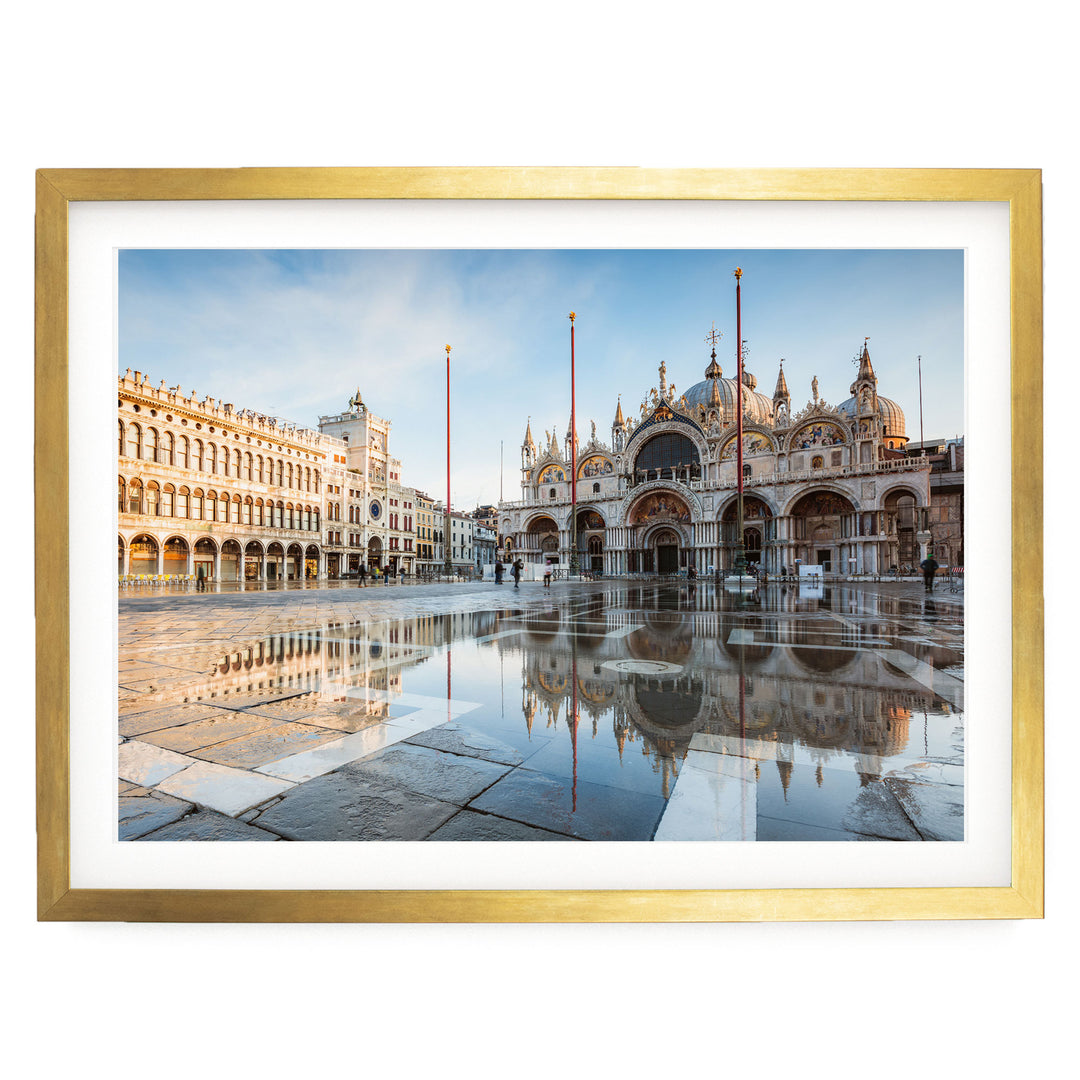a large, ornate building with multiple domes and arches, situated in a square with a reflective pool in the foreground. The building is surrounded by other buildings, creating a picturesque scene.