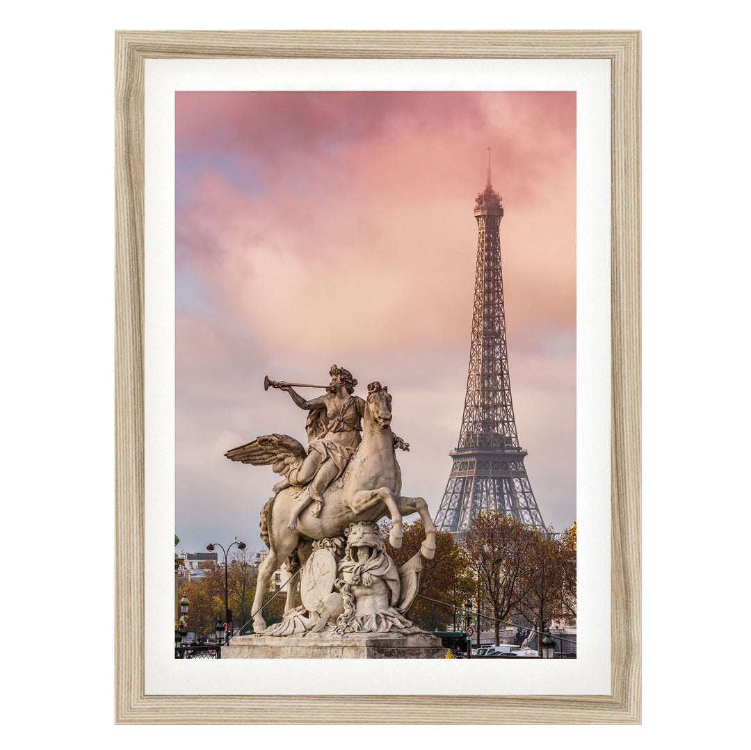 a statue of a winged man riding a rearing horse, with the Eiffel Tower visible in the background against a pink and purple sky.