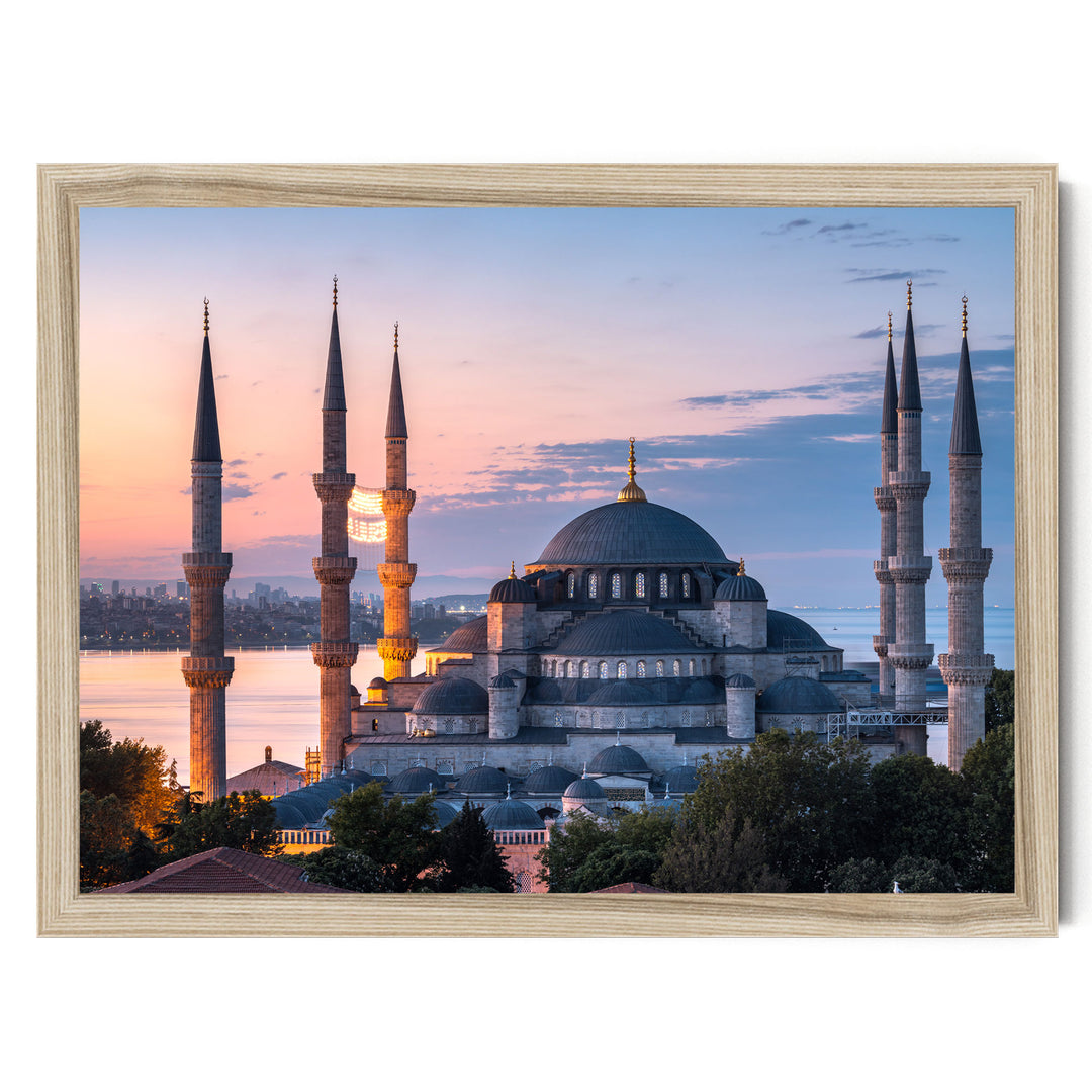 a large, ornate mosque with multiple minarets and domes, set against a colorful sunset sky.