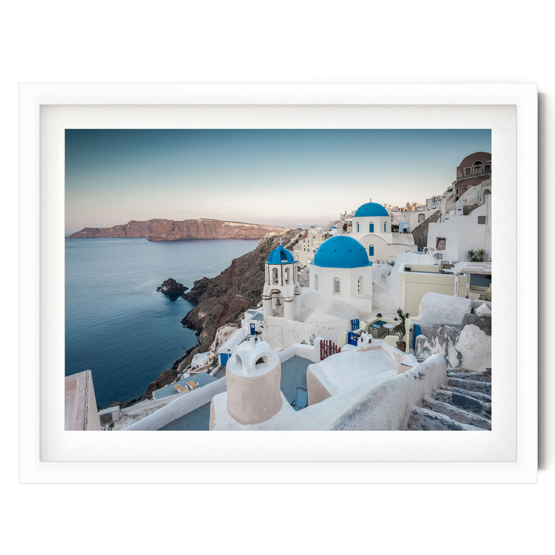 a picturesque coastal town with white buildings and blue domes, overlooking the ocean.