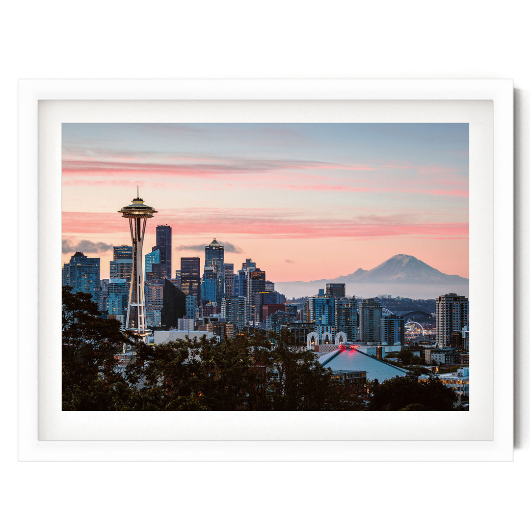 a city skyline at sunset, with the iconic Space Needle in the foreground and a mountain in the background.