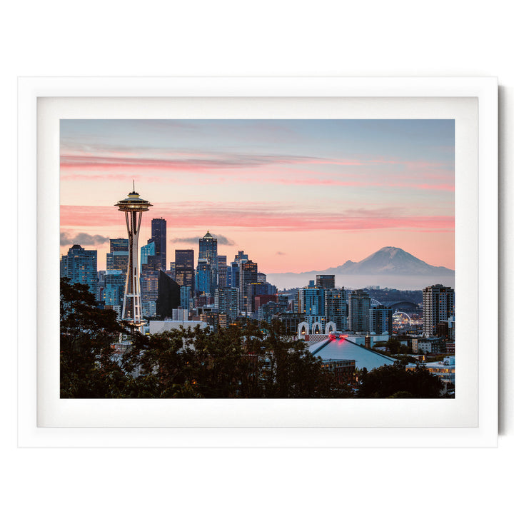 a city skyline at sunset, with the iconic Space Needle in the foreground and a mountain in the background.