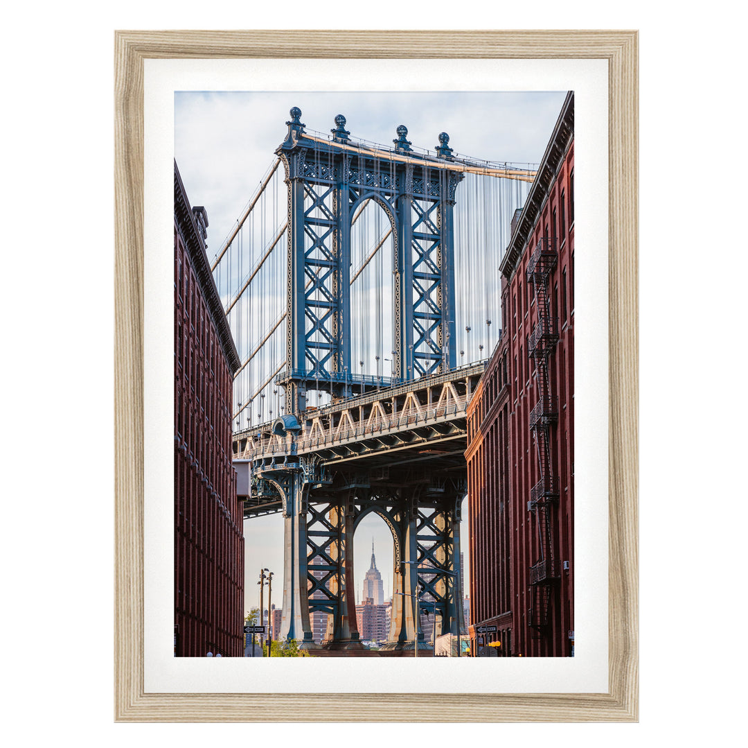a large suspension bridge with multiple towers and cables, spanning across a street with buildings on either side.