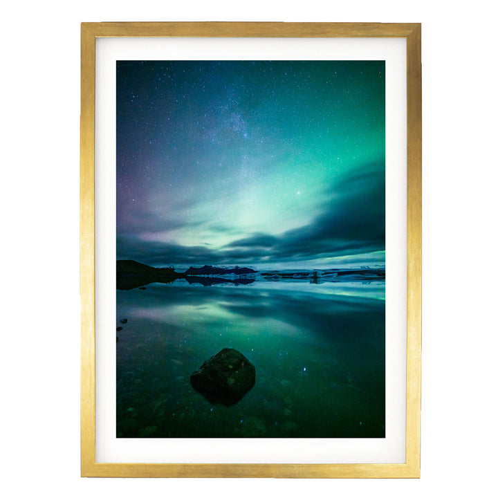 a serene night scene with a starry sky reflected in a calm body of water, surrounded by a rocky shoreline.