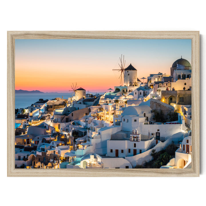 a picturesque coastal town in the Greek island of Santorini, with its iconic windmills and white buildings illuminated against the backdrop of a colorful sunset sky.