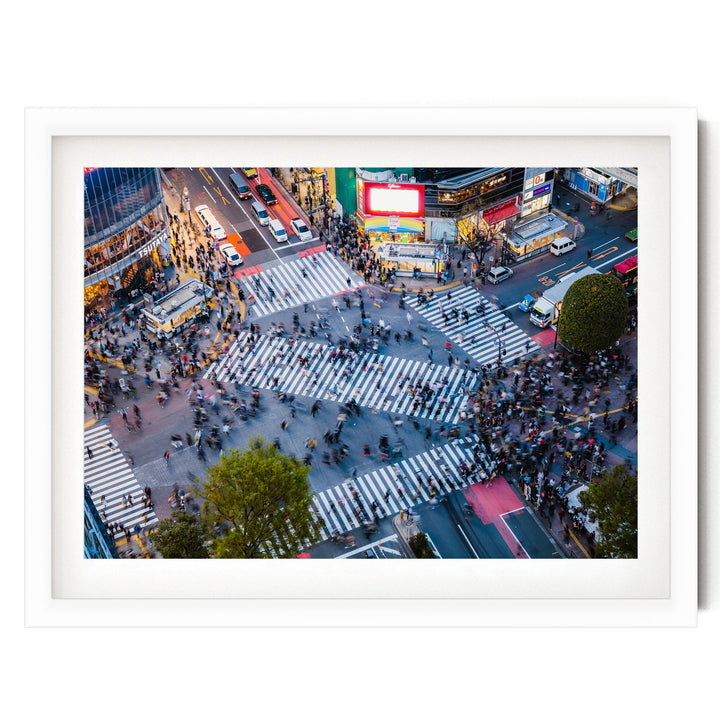 a busy city intersection with a large crowd of people crossing the street, surrounded by various vehicles and buildings.