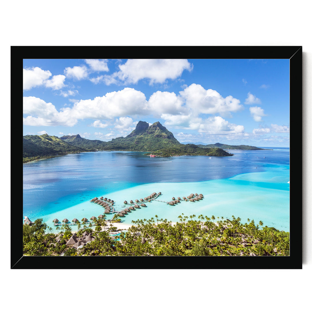 A stunning aerial view of a tropical island with crystal clear turquoise waters, lush green vegetation, and a majestic mountain range in the distance.