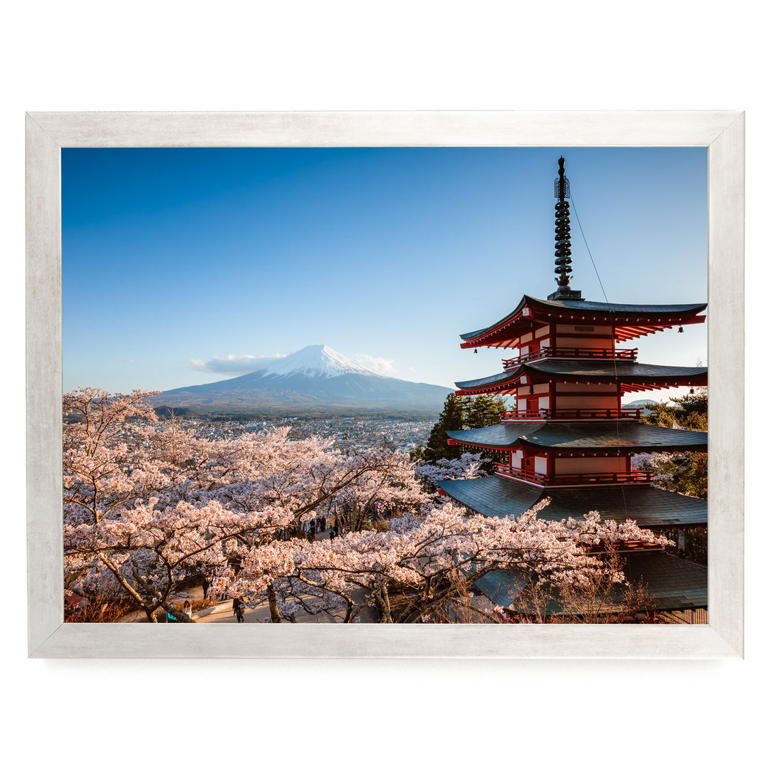 A traditional Japanese pagoda stands in the foreground, with cherry blossoms in full bloom in the background, overlooking a snow-capped mountain.