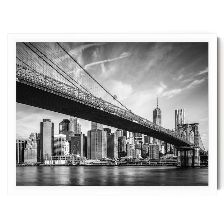 A black and white photograph of the Brooklyn Bridge spanning the East River, with the New York City skyline visible in the background.