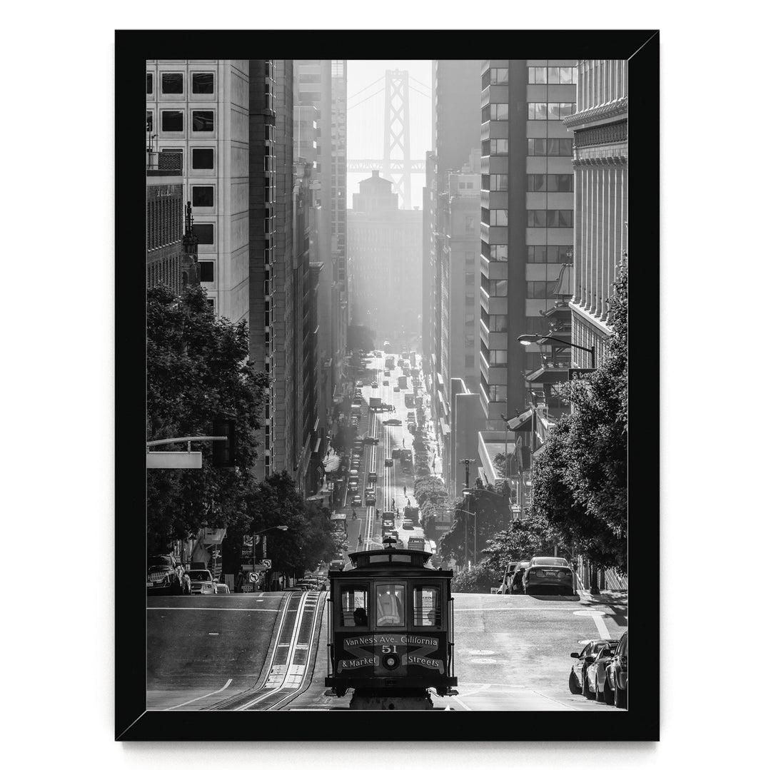 A black and white photograph of a trolley car traveling down a busy city street, surrounded by tall buildings and traffic.