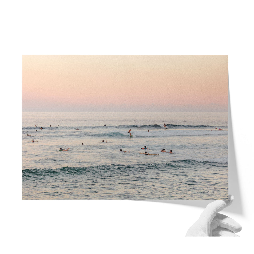 A group of people enjoying a day at the beach, with some swimming and others surfing in the ocean.