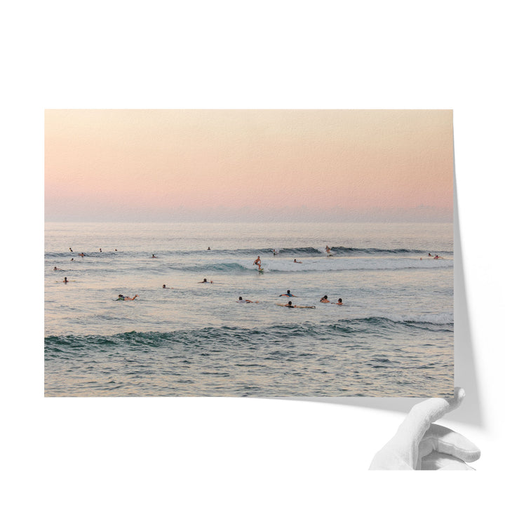 A group of people enjoying a day at the beach, with some swimming and others surfing in the ocean.