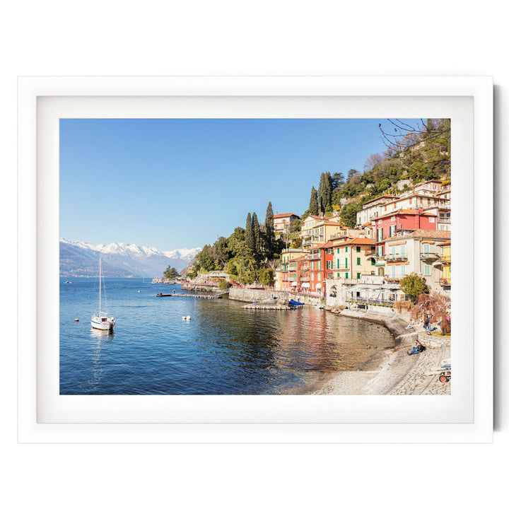 A picturesque coastal town with colorful buildings, a small boat on the water, and snow-capped mountains in the background.