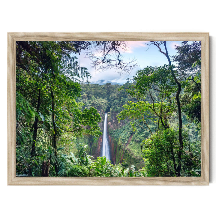 A lush, verdant forest with a towering waterfall cascading down the rocky cliff face, framed in a wooden frame.