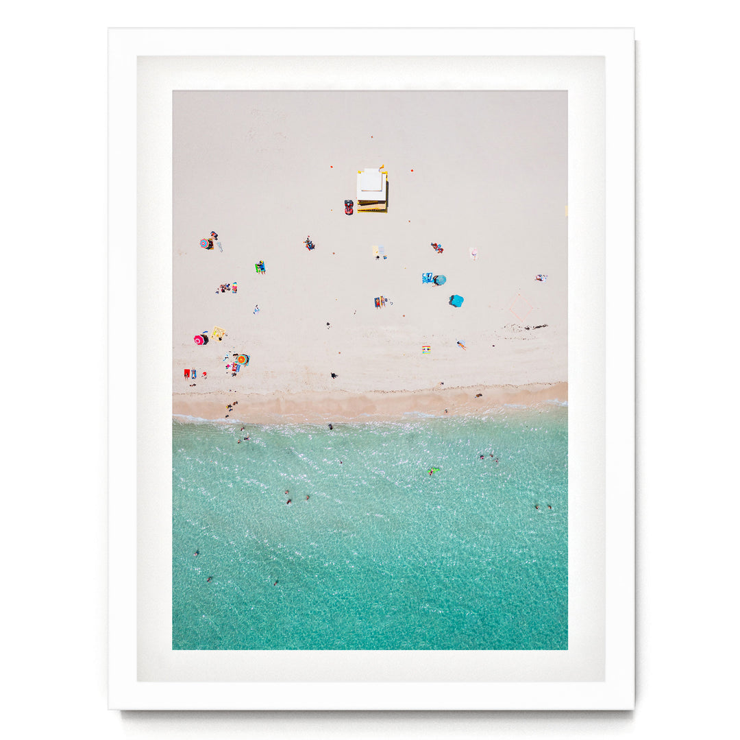 a beach scene with people enjoying the sun and the water, with a small white structure visible in the distance.