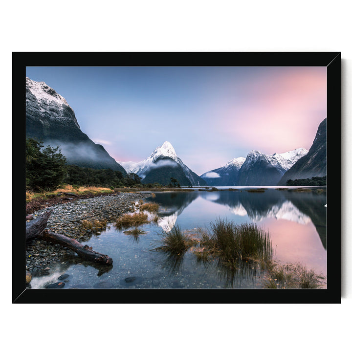 A serene landscape featuring a mountain lake with a rocky shore, surrounded by snow-capped peaks and a vibrant pink and blue sky.
