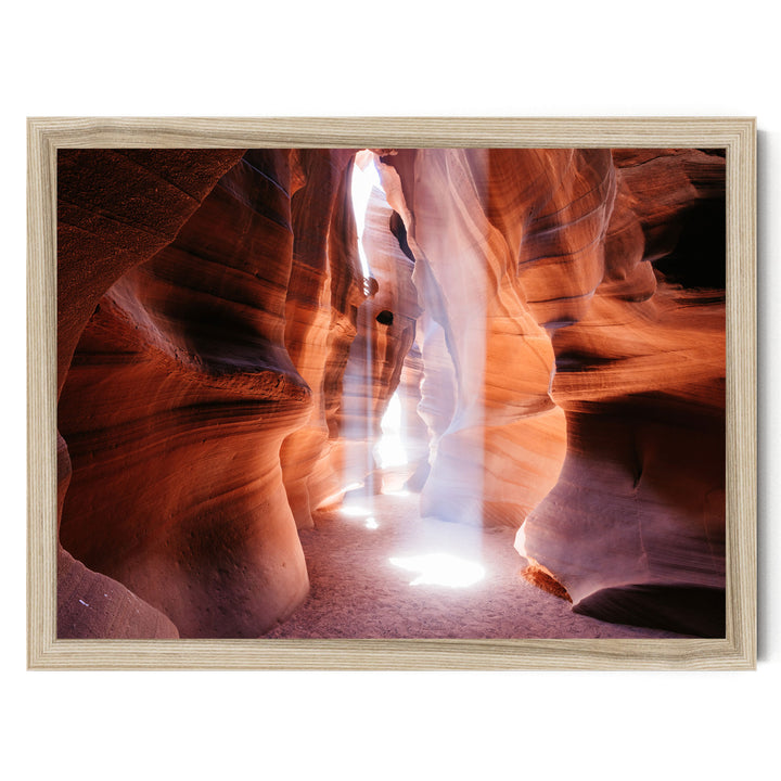 A framed photograph depicting a narrow, winding canyon with a bright light shining through the walls, creating a dramatic and atmospheric scene.