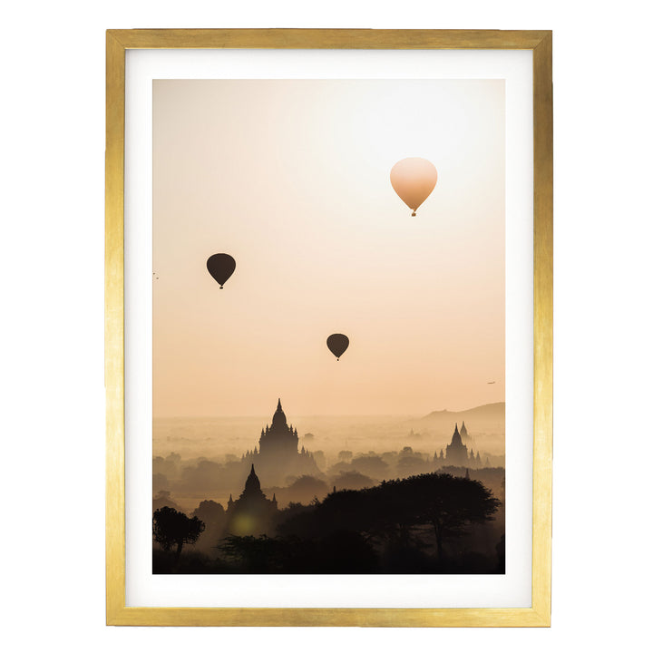 three hot air balloons floating in the sky above a cityscape with silhouetted buildings.