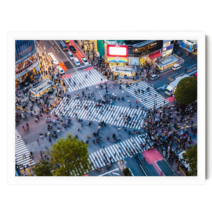 a busy city intersection with a large crowd of people crossing the street, surrounded by tall buildings and illuminated by colorful lights.