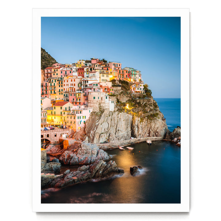 a picturesque coastal town nestled on a cliff, with its buildings painted in a vibrant array of colors and illuminated by warm lighting, creating a stunning and charming scene.