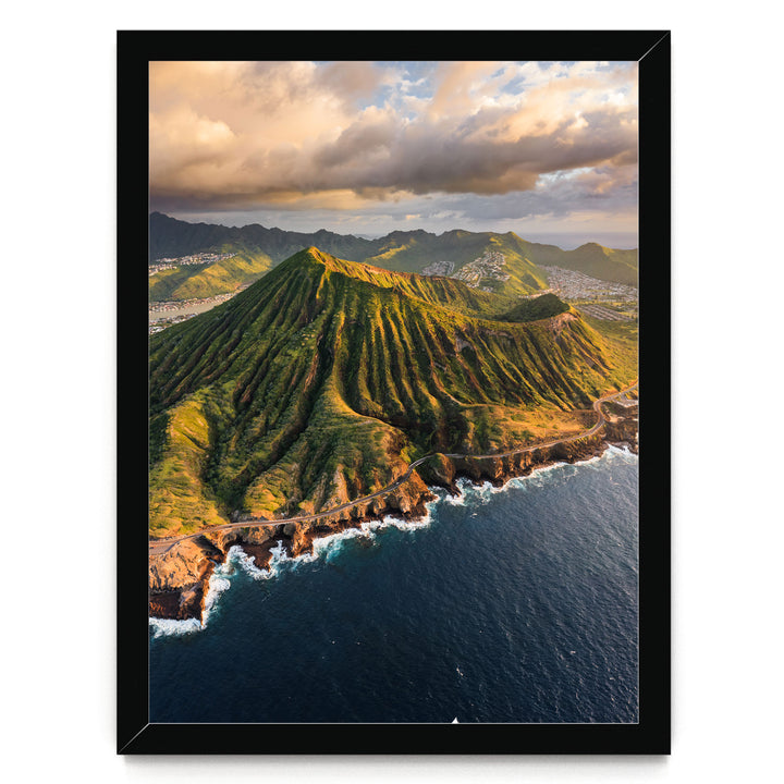 a stunning mountainous coastline with a winding road leading to the ocean. The landscape is covered in lush greenery, and the sky is filled with clouds, creating a dramatic backdrop. The overall scene is visually striking and captures the beauty of nature.