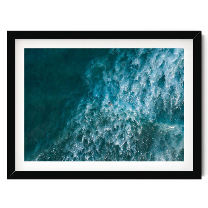 The image is a framed aerial view of a large body of water, likely an ocean, with waves and ripples visible.