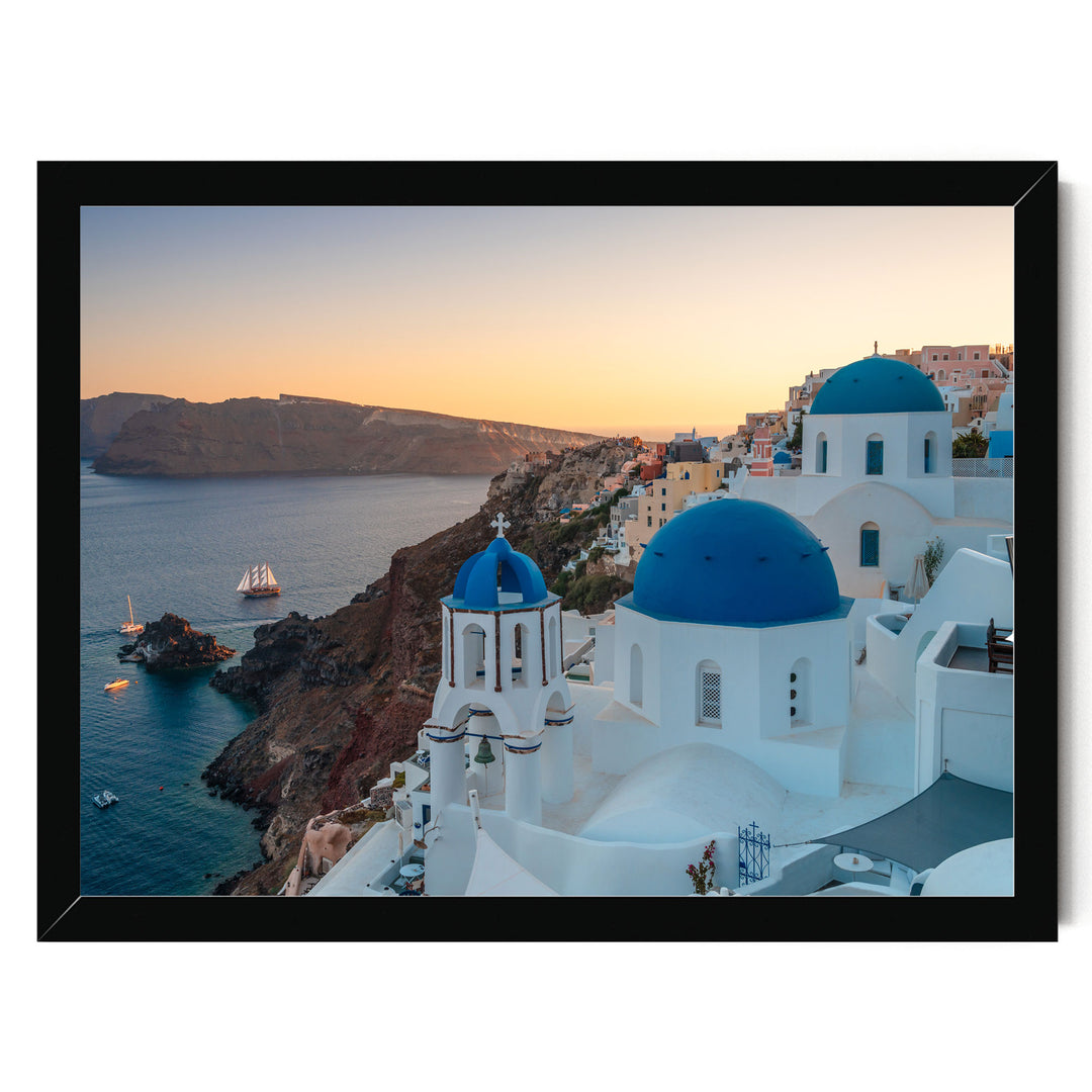 a picturesque coastal town with white buildings and blue domes, overlooking the ocean. The sun is setting, casting a warm glow over the scene.