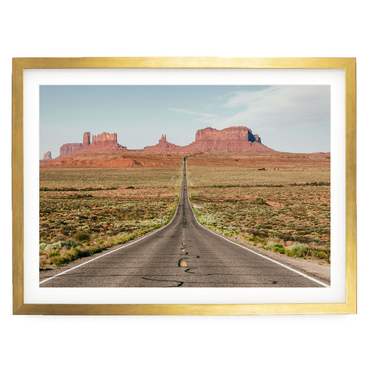 A long, straight road stretches out into the distance, leading towards a majestic mountain range in the background.