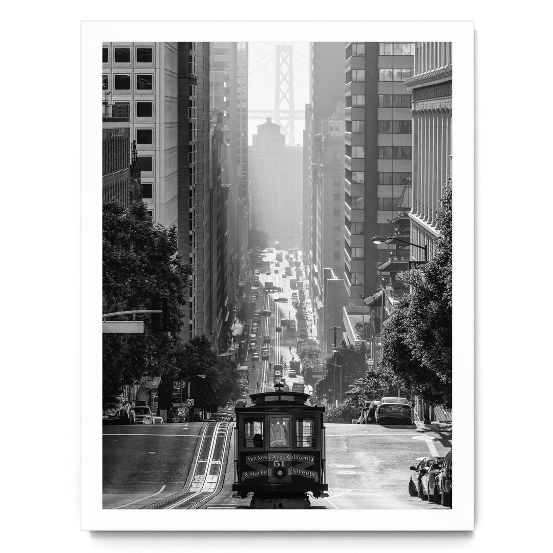 A black and white photograph of a cable car traveling down a steep, crowded city street with tall buildings on either side.