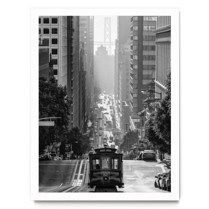 A black and white photograph of a cable car traveling down a steep, crowded city street with tall buildings on either side.