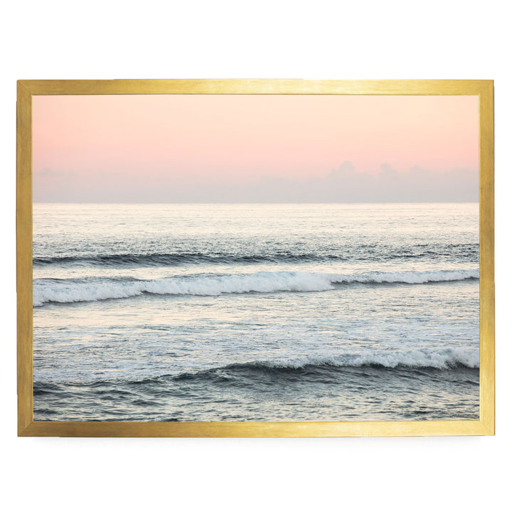 a serene ocean scene with waves gently lapping against the shore, set against a backdrop of a pink and orange sky.