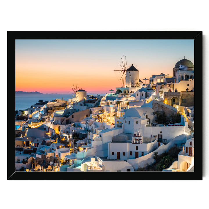 a picturesque coastal town with white buildings and windmills, illuminated at night against a backdrop of a colorful sunset sky.