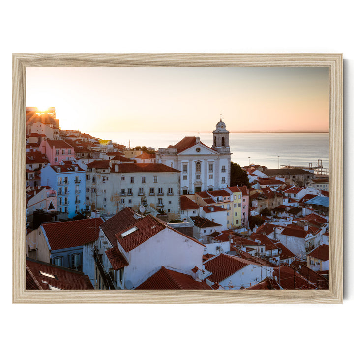 a picturesque town with a church and colorful buildings set against a backdrop of a sunset over the ocean.