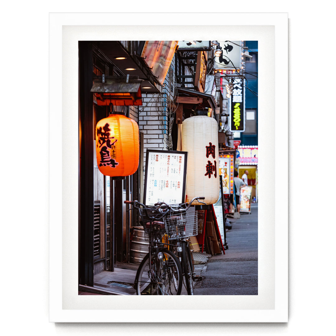 A bicycle parked on a street lined with colorful lanterns and signs, creating a vibrant and lively atmosphere.