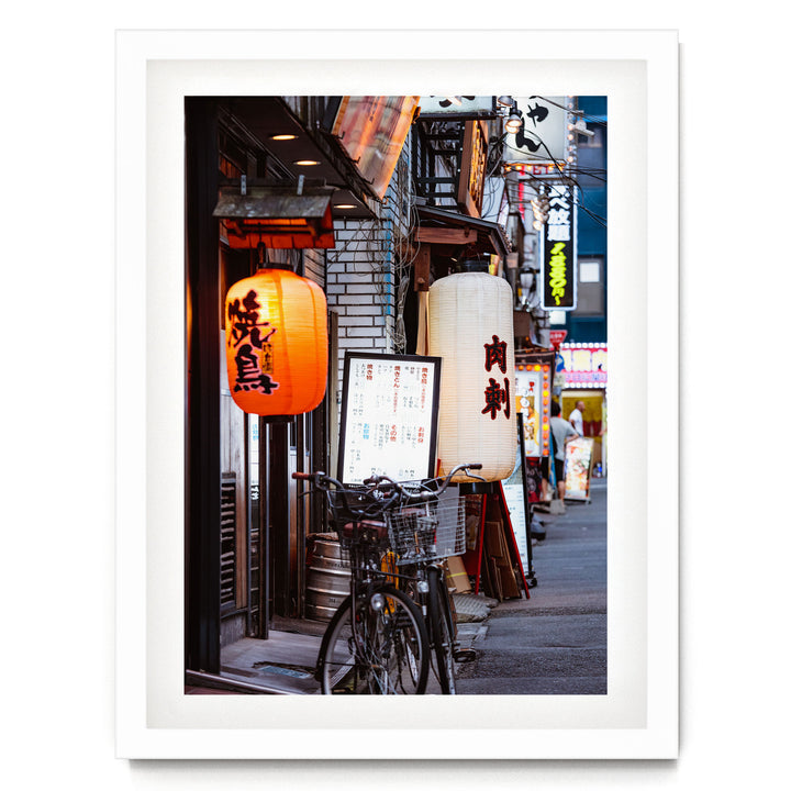 A bicycle parked on a street lined with colorful lanterns and signs, creating a vibrant and lively atmosphere.