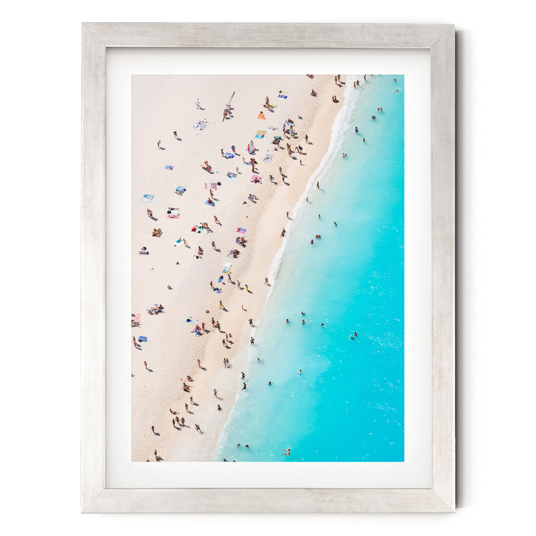 a crowded beach with people enjoying the sun and sand, with a clear blue ocean visible in the background.