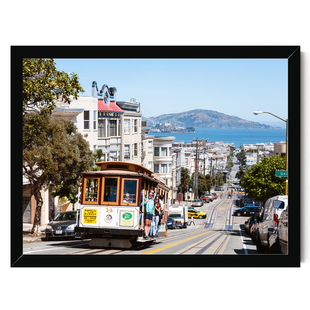 A cable car is traveling down a busy street in San Francisco, with buildings, cars, and pedestrians visible in the background.