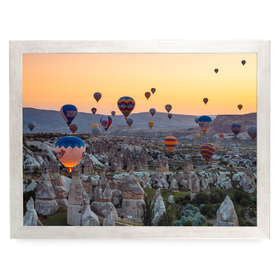 a breathtaking scene of hot air balloons floating over a mountainous landscape at sunset.