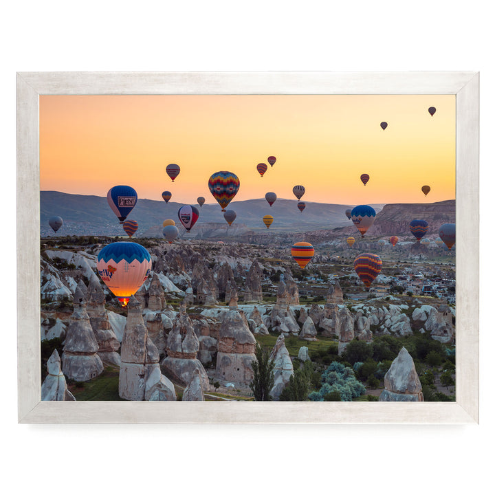 a breathtaking scene of hot air balloons floating over a mountainous landscape at sunset.