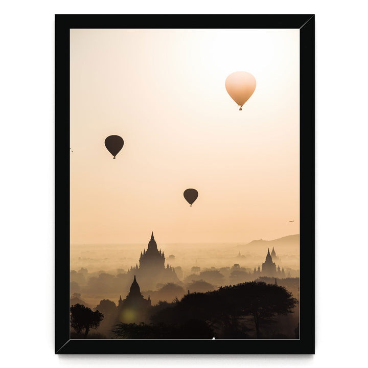 three hot air balloons floating in the sky above a cityscape with silhouetted buildings.
