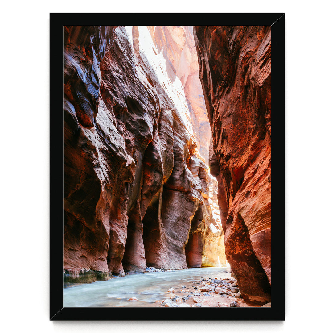 A framed image depicting a narrow, winding river flowing through a canyon with towering red rock walls on either side.